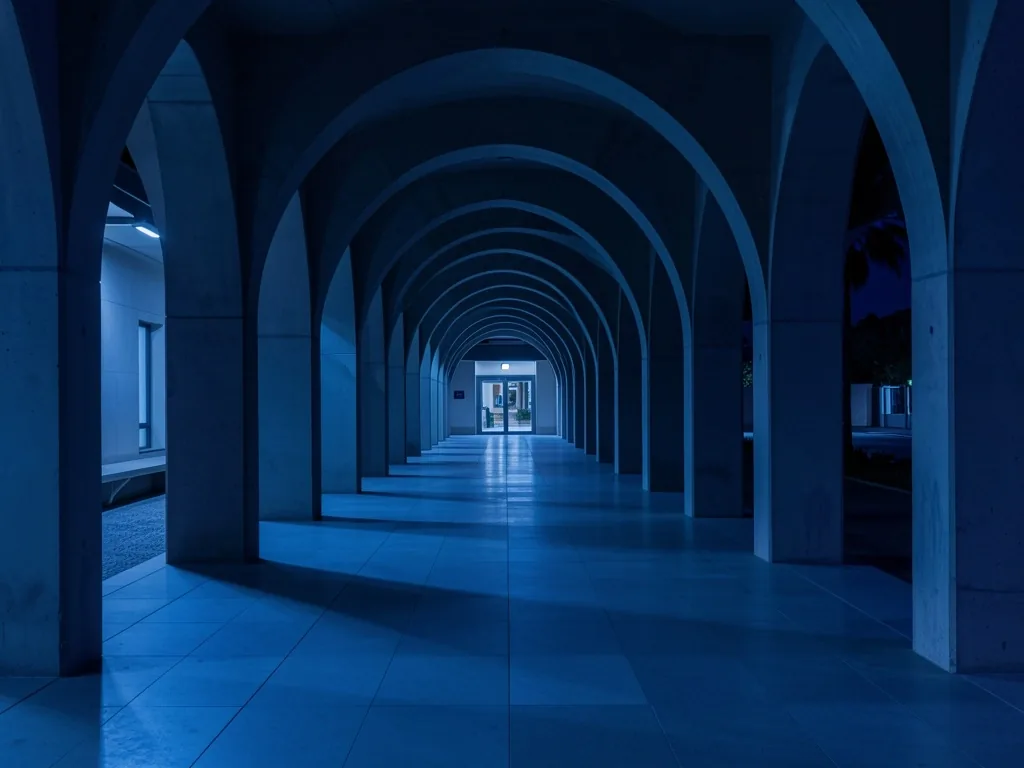 Corredor institucional con arcos de hormigón bajo luz nocturna